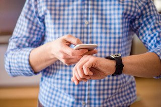 Unrecognizable man at home using smartphone and smart watch