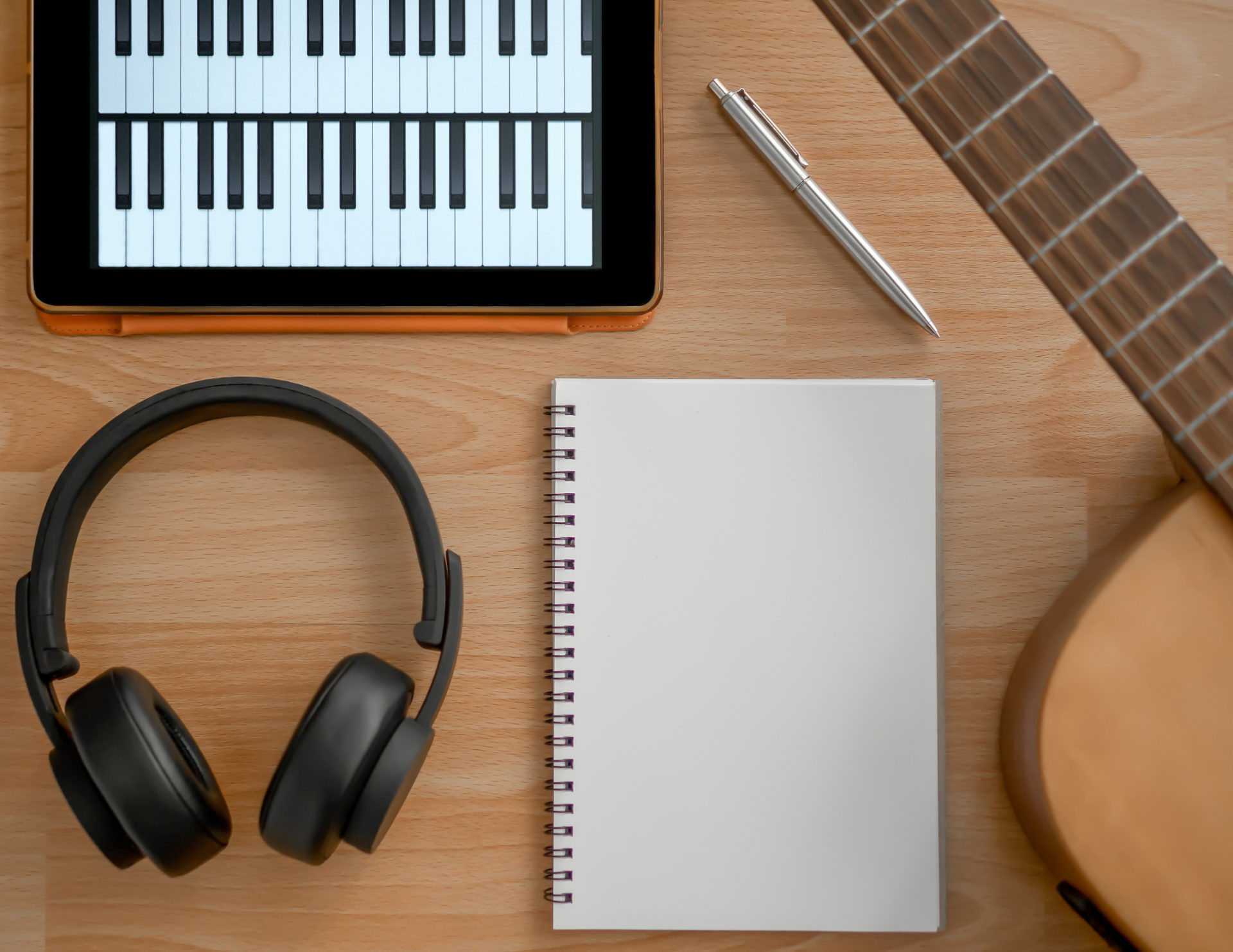 Image of notebook with guitar, headphones, and piano tablet.